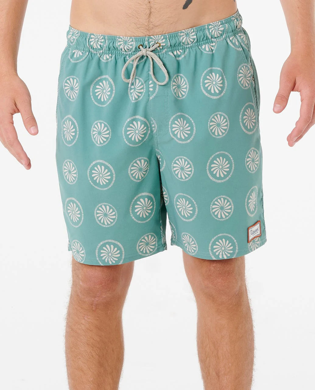 Teal swim shorts with white pattern worn by a person on a white background