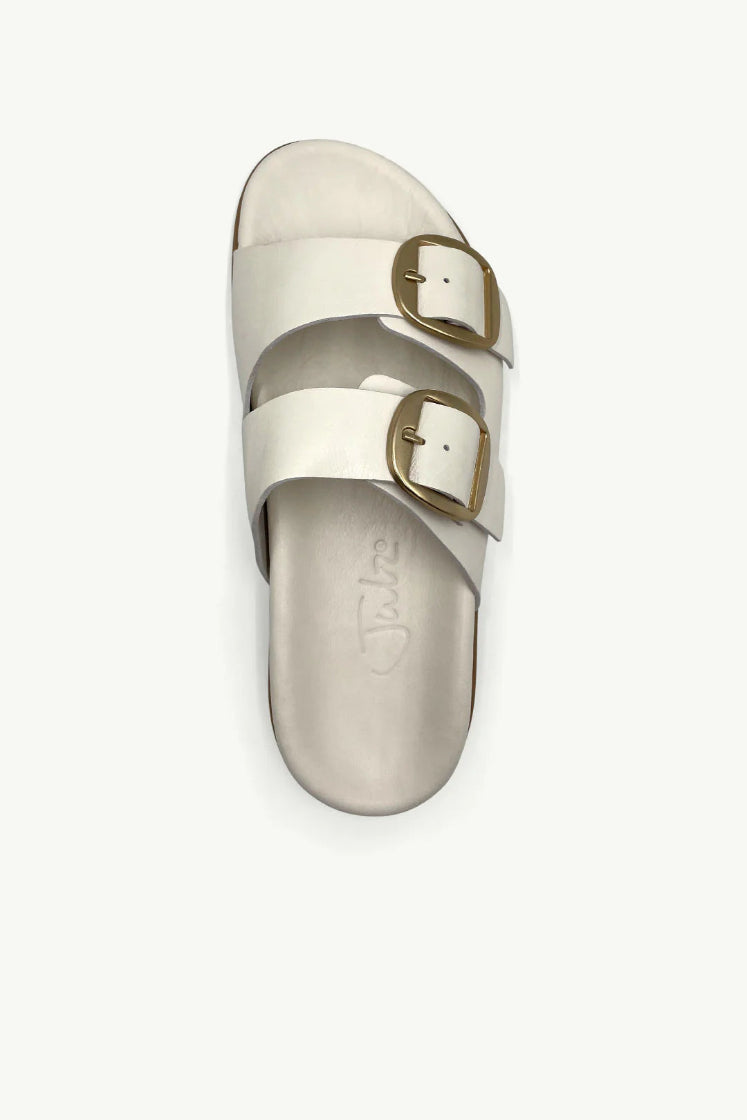 Top view of neutral leather sandal with gold buckles against a studio background