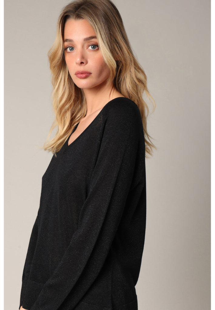 Woman wearing a black sweater against a neutral background