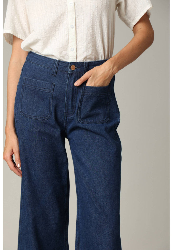 Person wearing blue jeans and a white shirt on a plain background