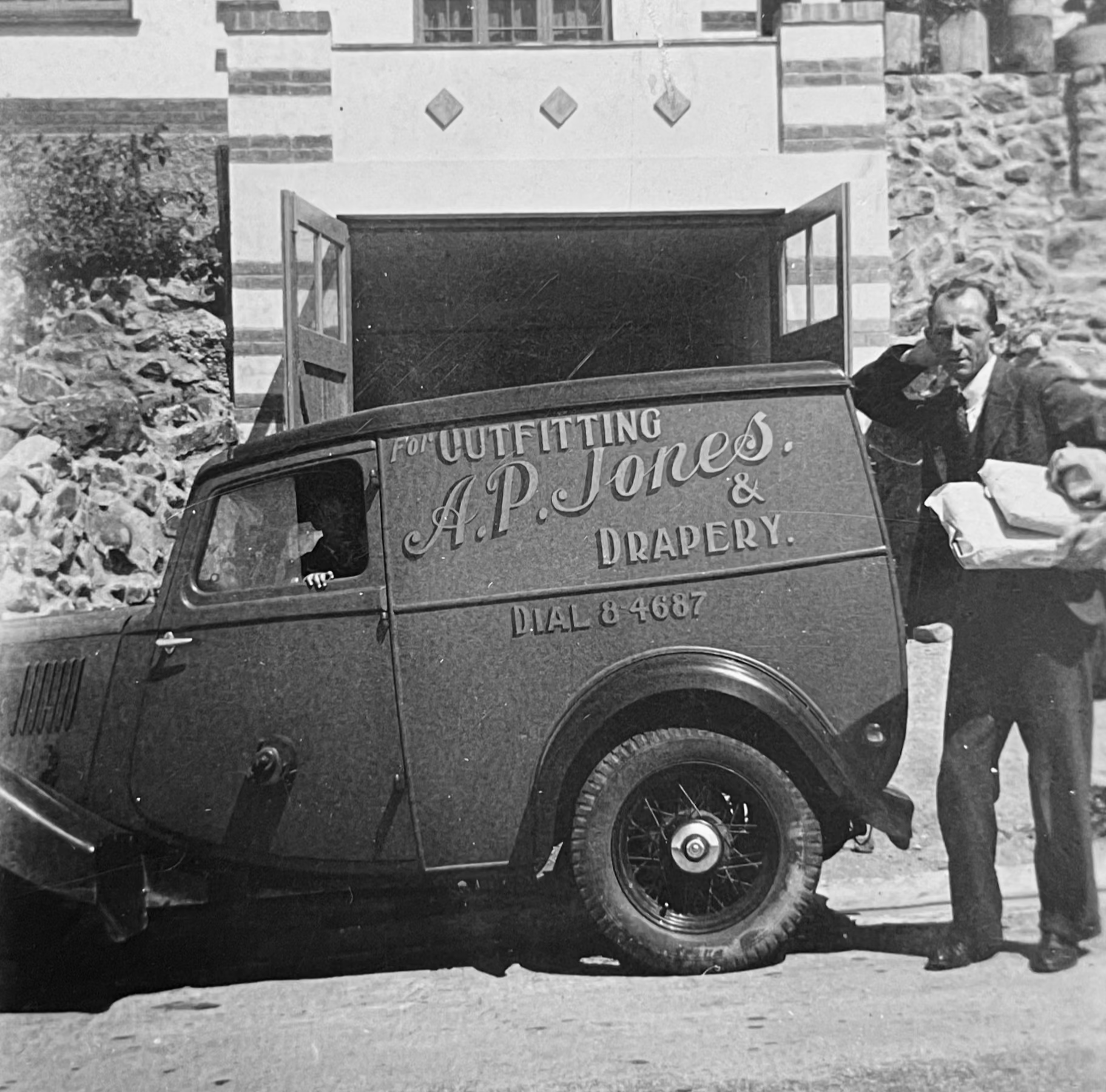 Vintage truck with 'A.P. Jones & Drapery' branding parked in front of a building.