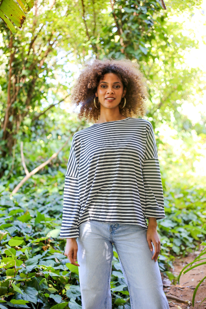 Woman wearing a striped shirt and jeans standing in a forest