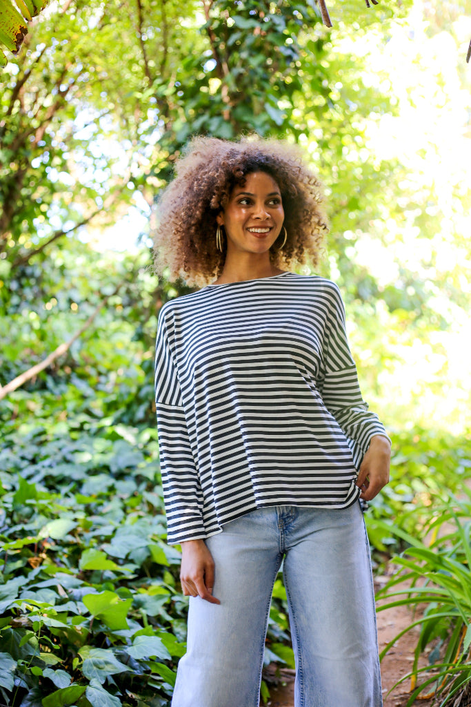 Woman wearing a striped shirt and jeans standing in a forest