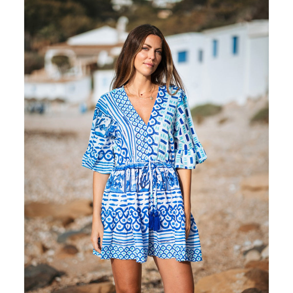 Woman wearing a blue and white patterned dress on a beach.