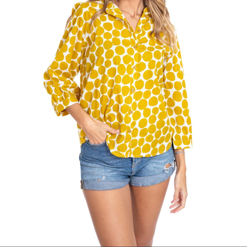 Woman wearing a yellow polka dot shirt and denim shorts on a white background
