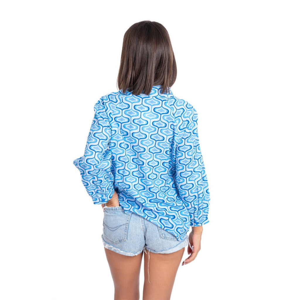 Person wearing a blue patterned shirt and denim shorts on a white background