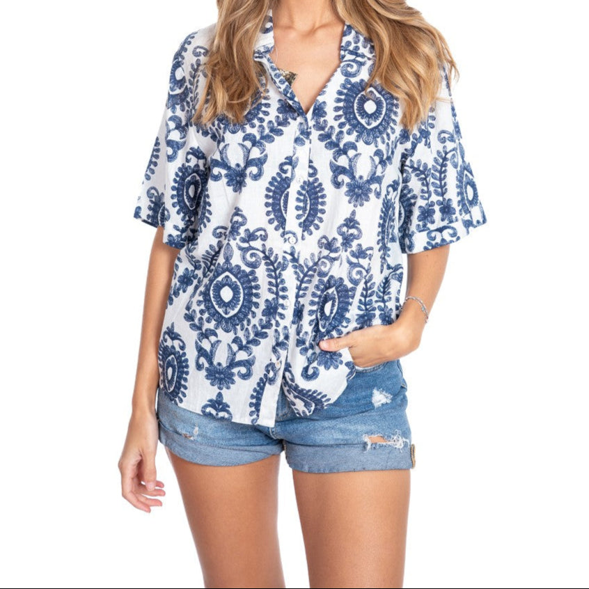 Woman wearing a blue and white patterned shirt with denim shorts on a white background