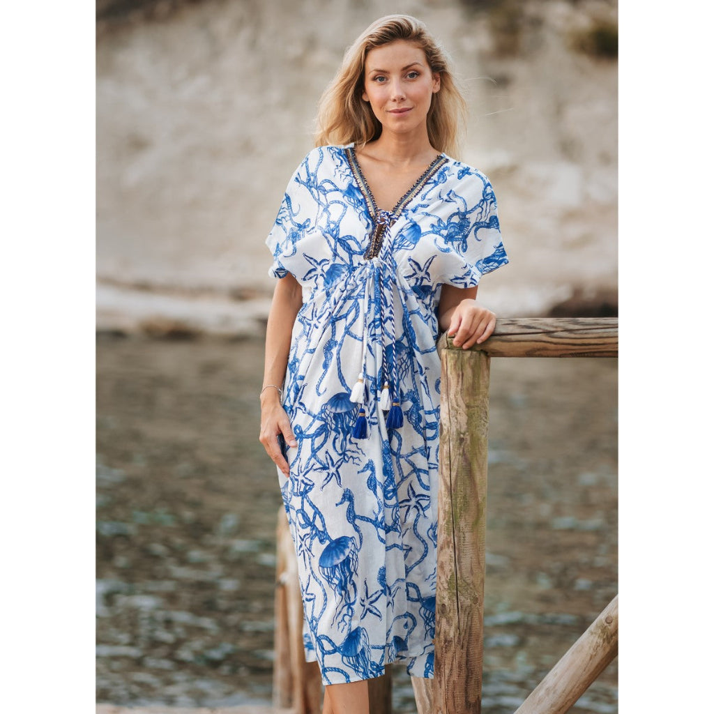 Woman wearing a blue and white patterned dress by a body of water.