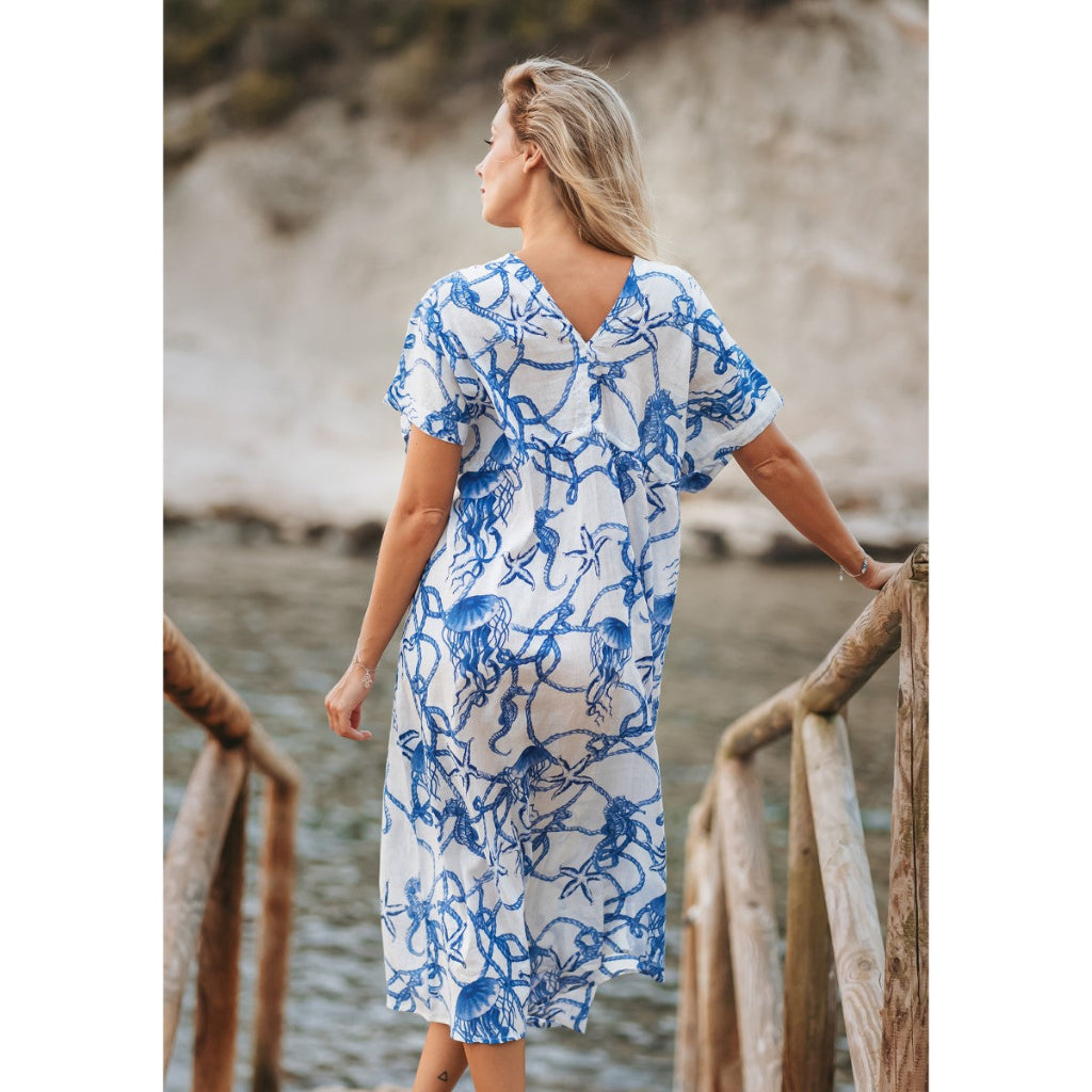Woman wearing a blue and white patterned dress by a body of water.