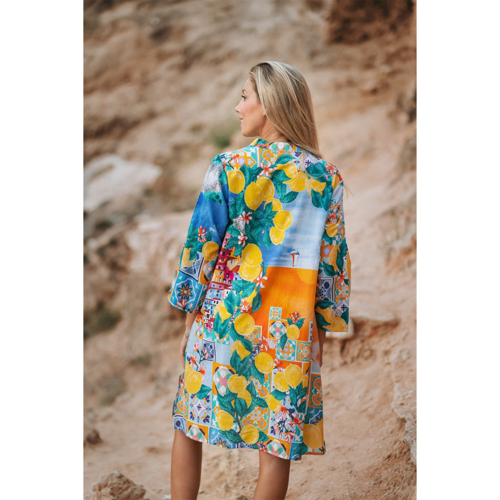 Woman wearing a colorful kimono-style dress with lemon pattern in a natural setting