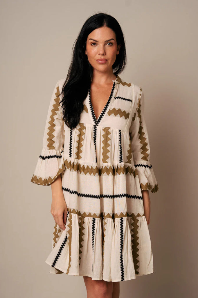 Woman wearing a patterned dress against a plain background