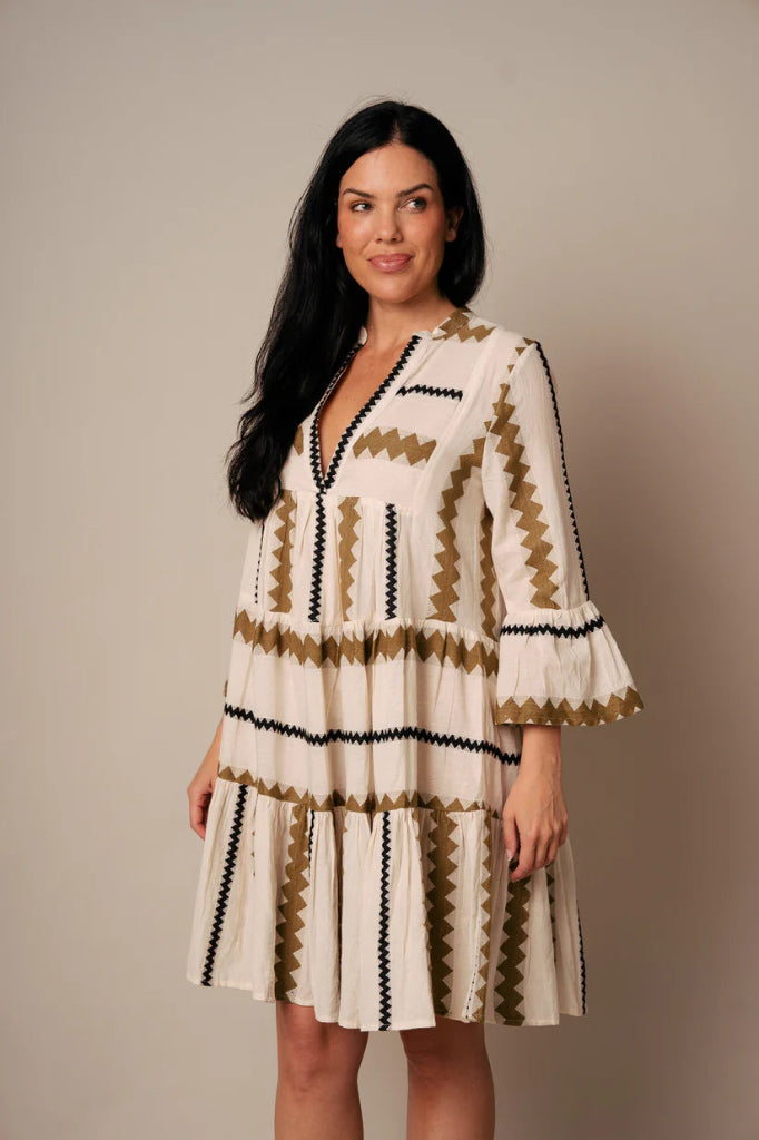 Woman wearing a patterned dress against a plain background