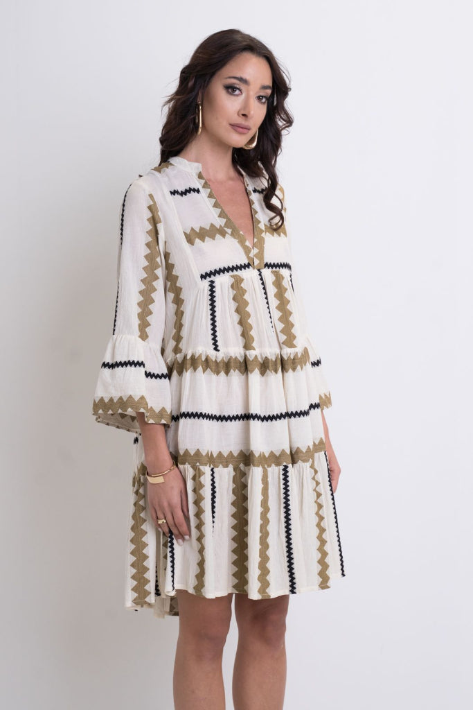 Woman wearing a white dress with black and gold patterns on a white background