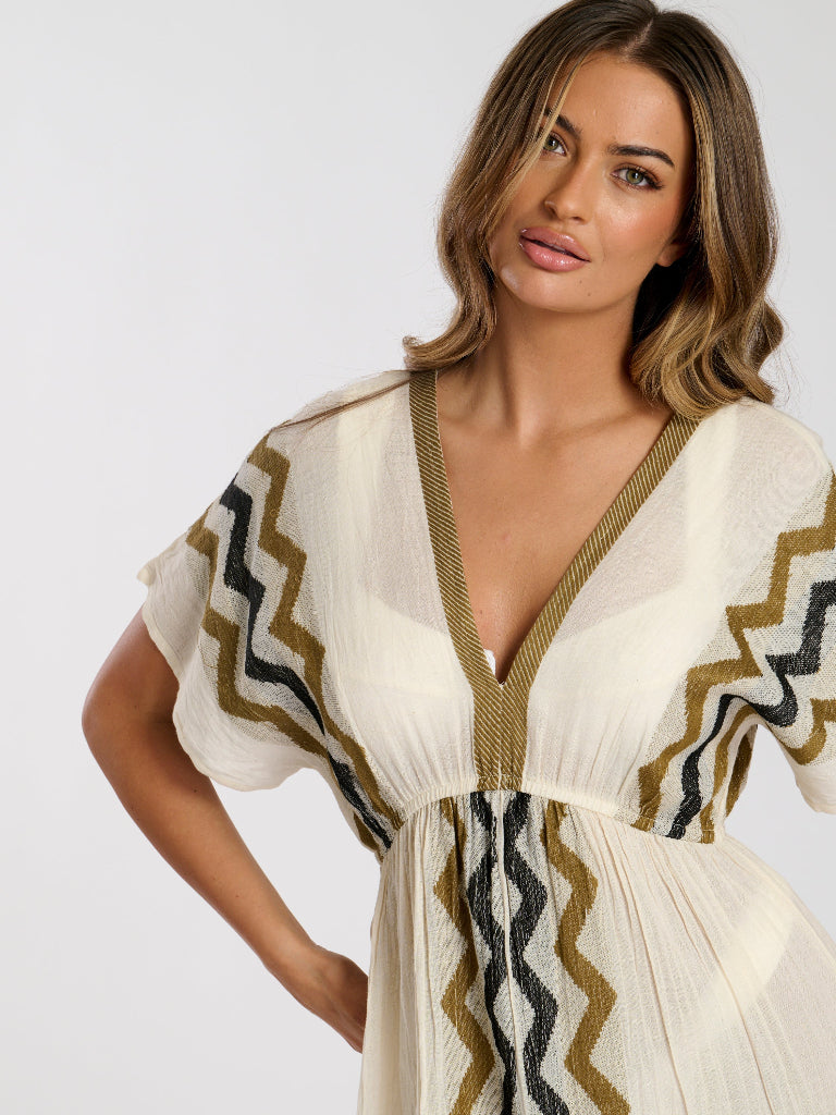 Woman wearing a white dress with geometric patterns on a plain background