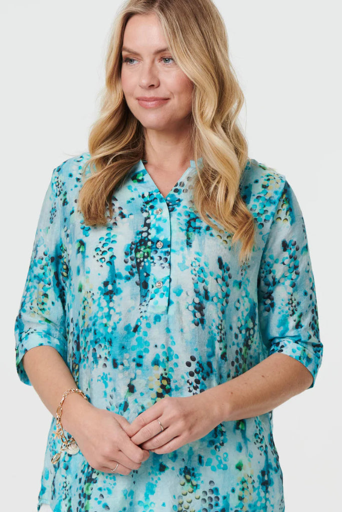 Woman wearing a blue and green patterned blouse against a white background
