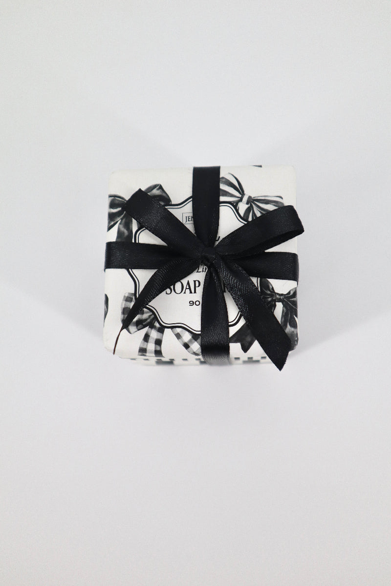 Bar of soap in a decorative box with a black ribbon on a white background
