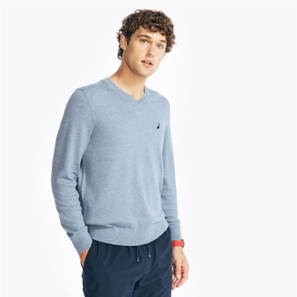 Man wearing a light blue sweater with a brand logo on a white background