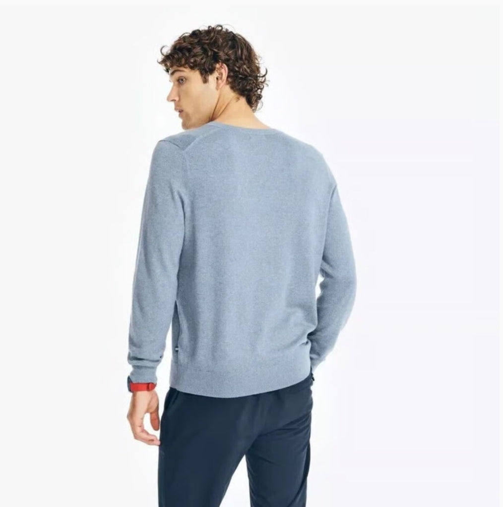 Man wearing a light blue sweater and dark pants on a white background