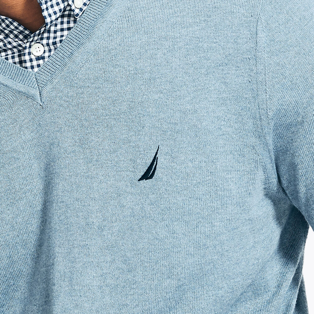 Close-up of a light blue sweater with a small logo on the chest.