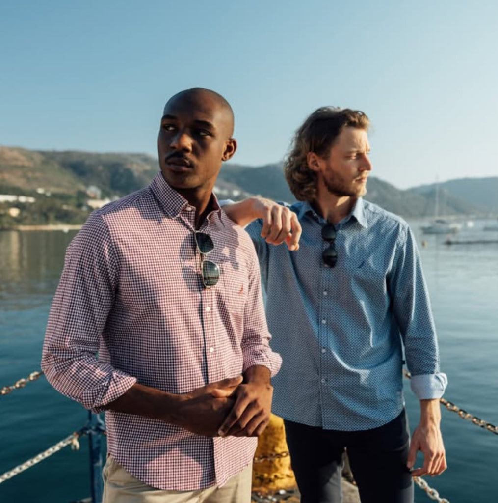 red gingham button down shirt Two men standing by a waterfront with mountains in the background