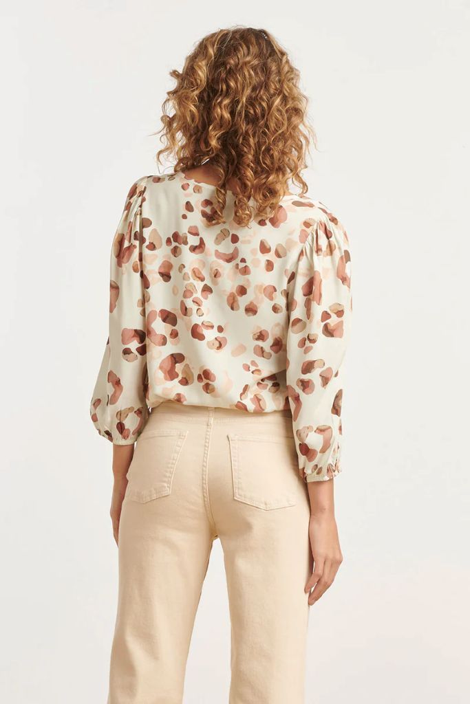 Woman wearing a floral blouse and beige pants on a white background