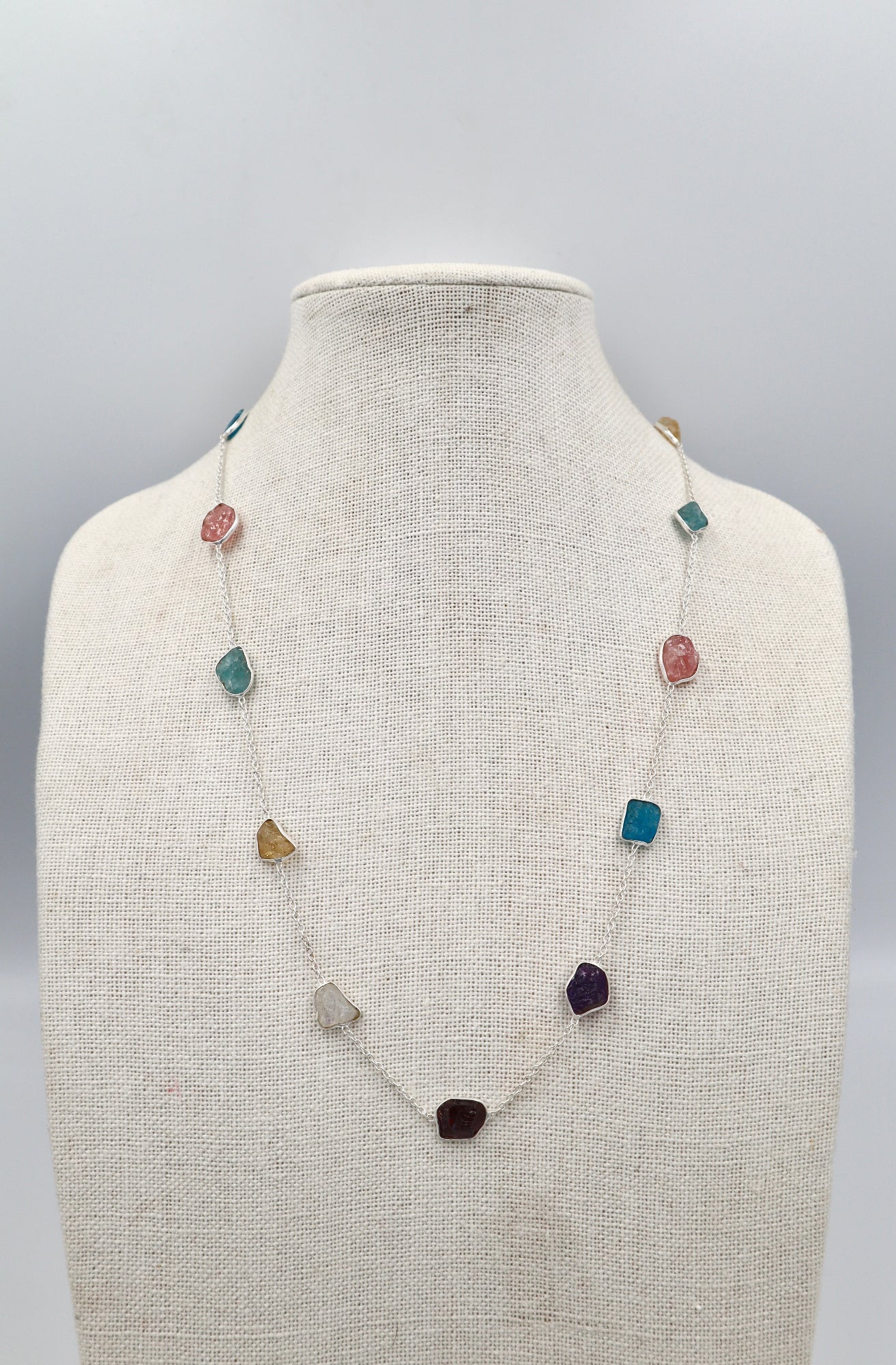 Necklace with multicolored gemstones on a mannequin bust against a gray background