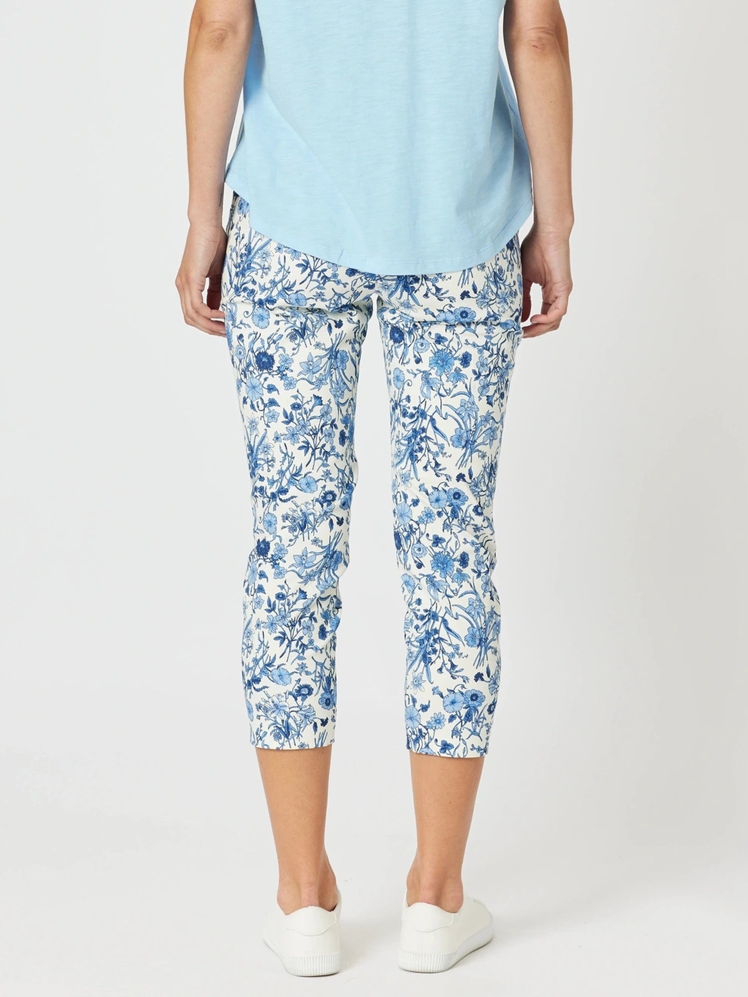 Person wearing blue floral capri pants on a white background