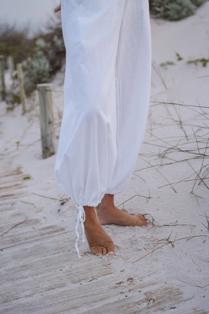 Person wearing white pants standing on a sandy beach.