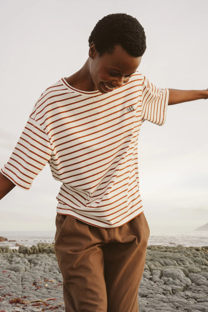 Person wearing a striped shirt and brown pants on a beach