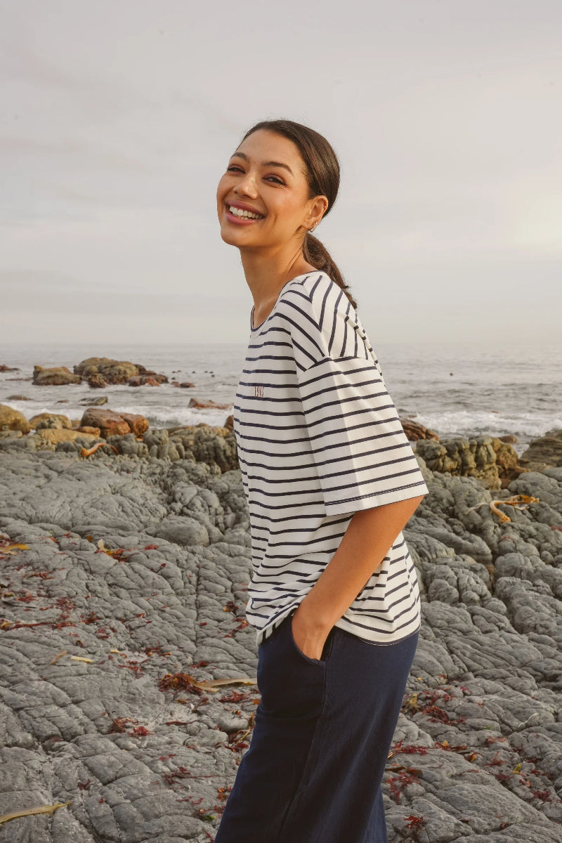 Woman in a striped shirt standing on a rocky beach