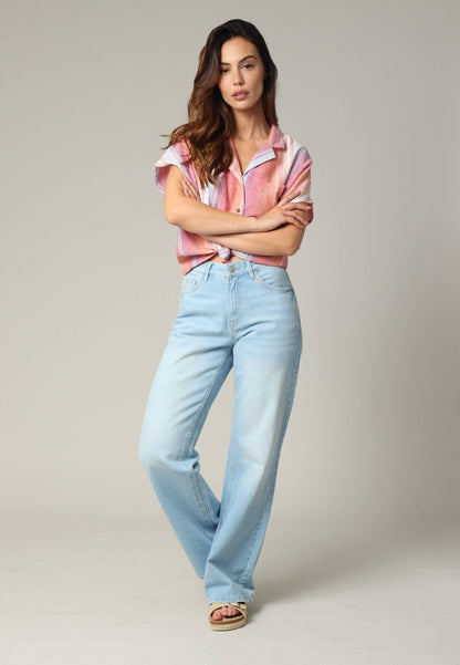 Woman wearing a striped shirt and light blue jeans against a plain background