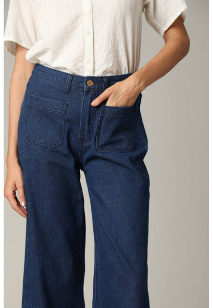 Person wearing blue jeans and a white shirt on a plain background