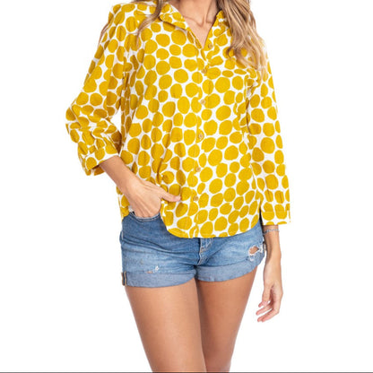 Woman wearing a yellow polka dot shirt and denim shorts on a white background