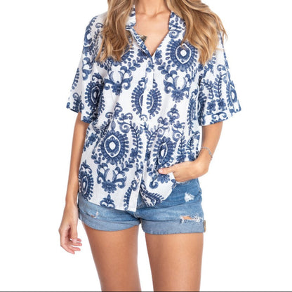 Woman wearing a blue and white patterned shirt with denim shorts on a white background