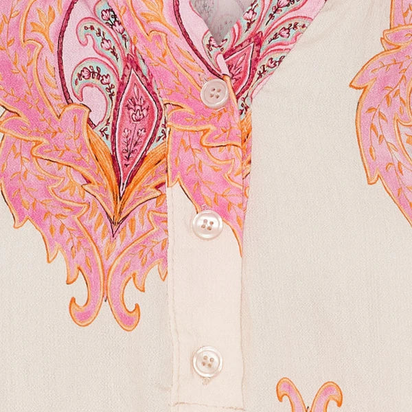 Close-up of a dress with pink and orange paisley pattern on a beige background
