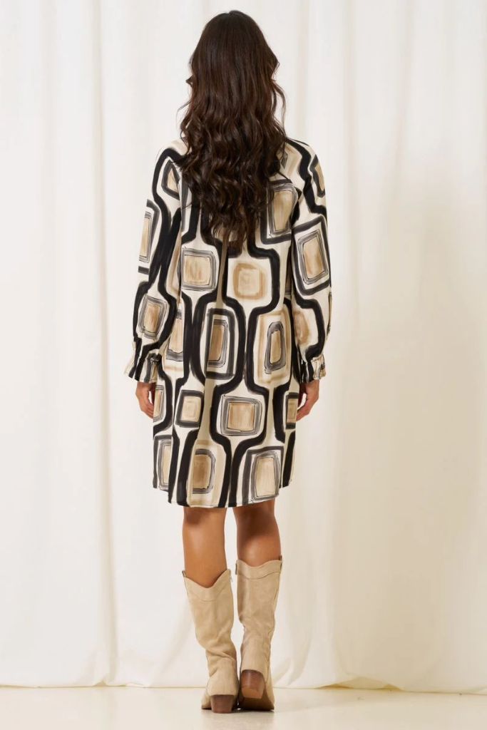 Person wearing a patterned  Marta Du Chateau Estella dress and knee-high boots against a white curtain background