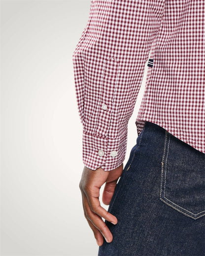 Red and white checkered shirt with rolled-up sleeves and dark jeans on a light gray background
