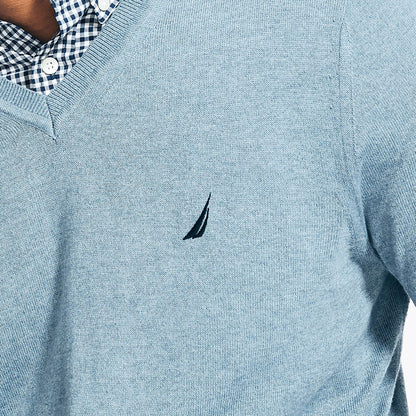 Close-up of a light blue sweater with a small logo on the chest.