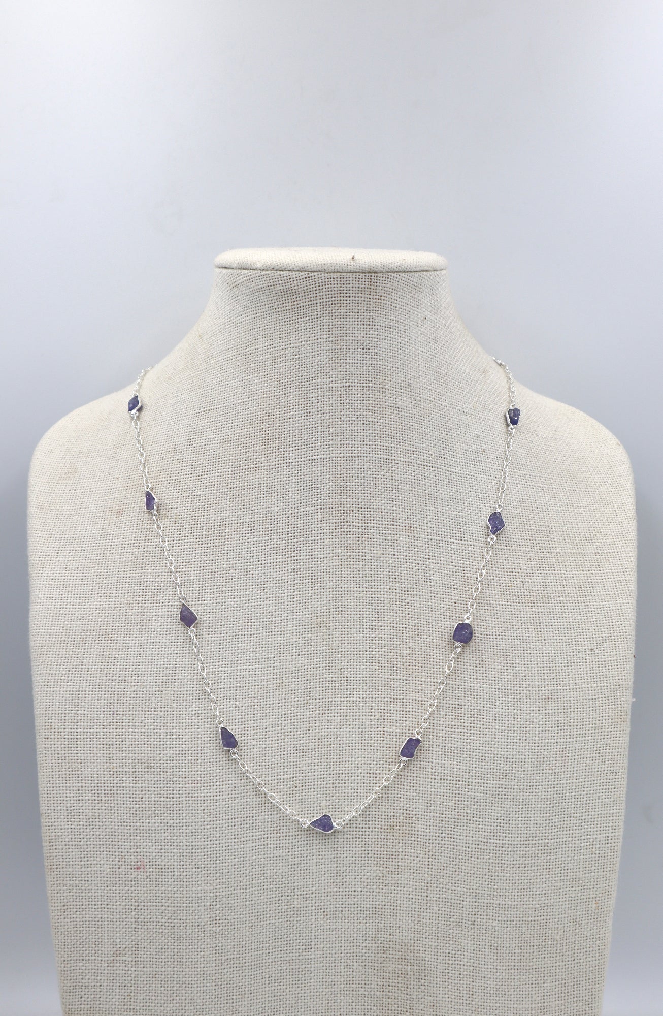Necklace with purple stones on a mannequin bust against a gray background