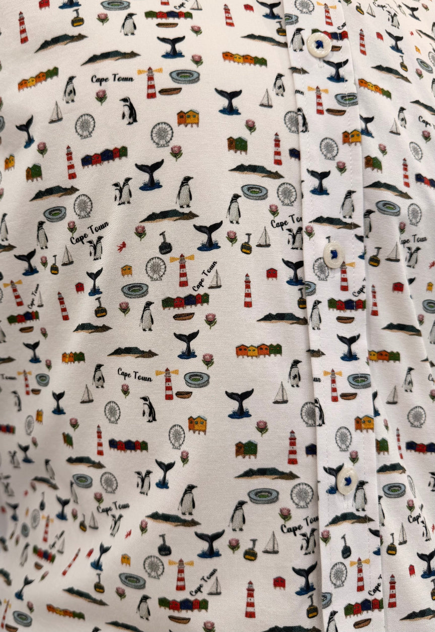Close-up of a white fabric with an all-over nautical print featuring penguins, penguins, whales, lighthouses, sailboats, and the words 'Cape Town'.