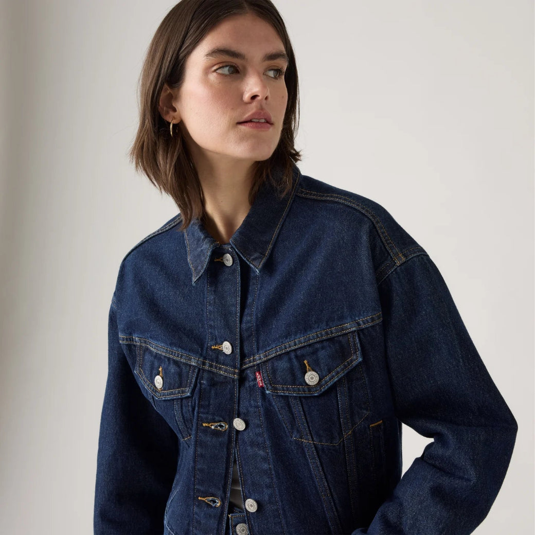Woman wearing a blue denim jacket on a plain background
