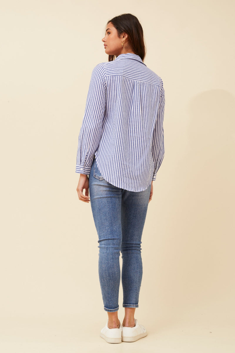Woman wearing a blue and white striped shirt and jeans on a beige background